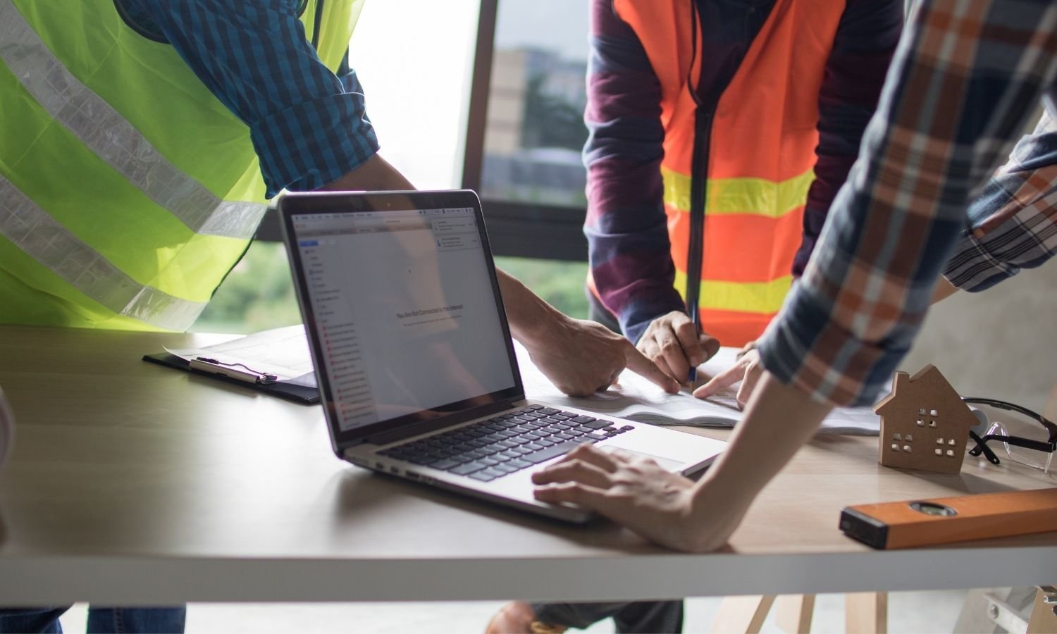 Engineer using a laptop to analyze project plans, emphasizing expert digital services for construction and infrastructure businesses.