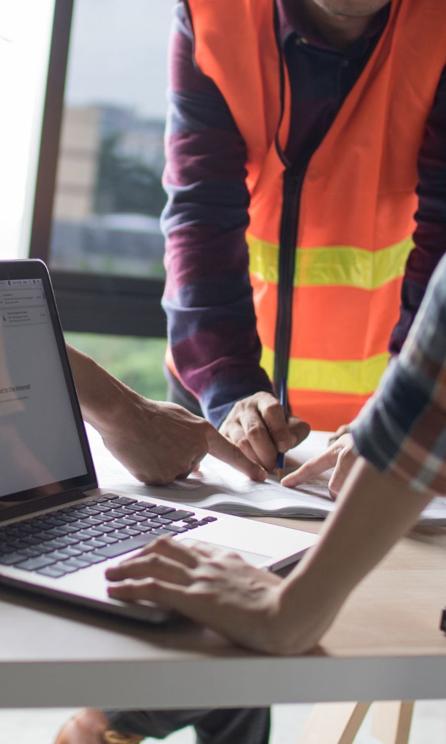 Engineer reviewing construction site plans on a laptop, symbolizing tailored digital services for industry leaders in construction and engineering.