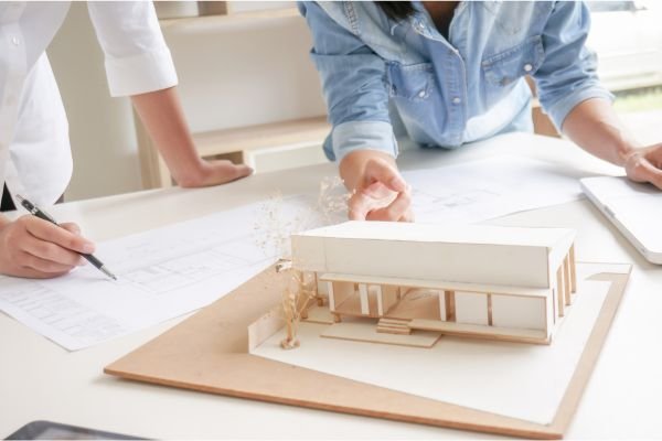 Engineers reviewing a scaled home model and blueprints, highlighting Infrastructure Tech Services’ tailored web design and SEO services for construction and engineering firms.