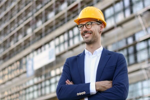Smiling architect standing at a new development site, illustrating Infrastructure Tech Services’ digital marketing and custom web design expertise for the AEC industry.